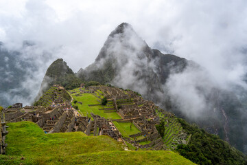 Panoramic view of Machu Picchu ruins surrounded by misty mountains, Peru