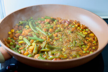 vegetables are cooked in a frying pan in a home kitchen