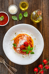 Spaghetti marinara - pasta with tomato sauce, parmesan cheese and basil leaves on wooden table	