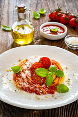 Spaghetti marinara - pasta with tomato sauce, parmesan cheese and basil leaves on wooden table	