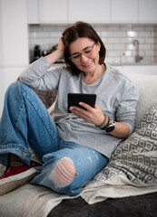 Obraz premium Girl Reading E-Book On Sofa At Home