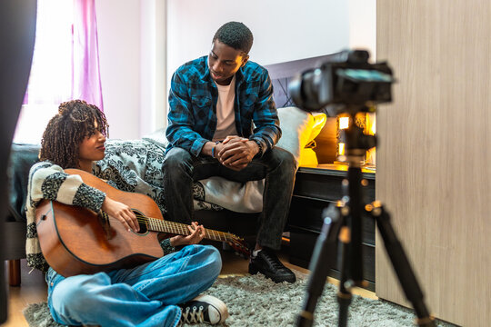 Young musicians composing a song, playing acoustic guitar and recording video with camera