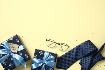Father's Day flat lay border with gift boxes, necktie, glasses, and confetti on yellow background. Top view with copy space.