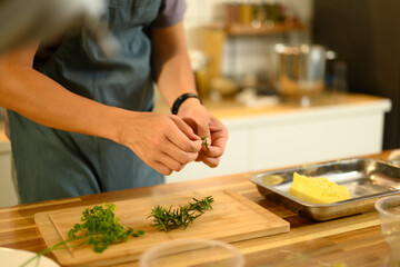 Obraz premium Chef preparing fresh herbs on cutting board to mix into homemade butter