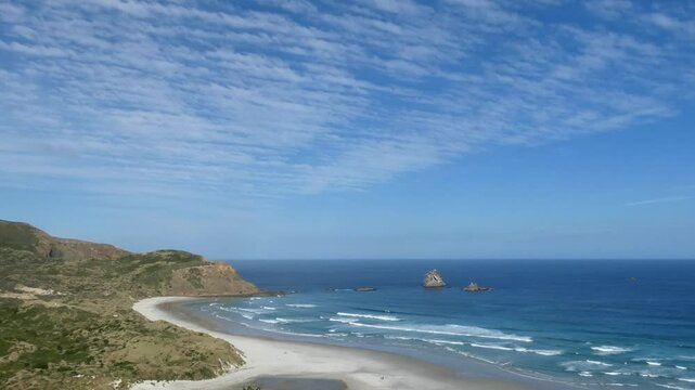 Cirrus Clouds appear almost stationary above the stunning Sandfly Bay Wildlife Refuge in summertime (Otago Peninsula, New Zealand)