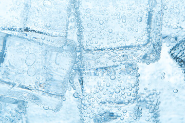 Refreshing soda water with ice cubes as background, closeup