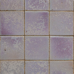 A close-up view of square tiles in various soft lavender hues
