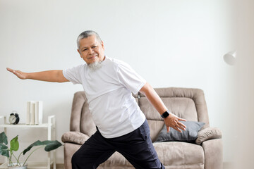 Fototapeta premium Asian old man is doing a yoga pose in a living room
