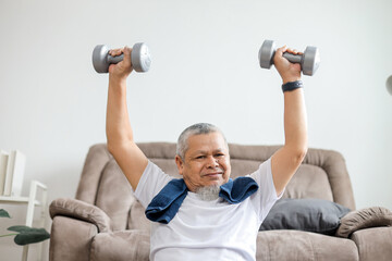 Asian senior man lifting dumbbells during morning workout at home