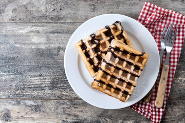 Belgian Waffles with chocolate on on wooden table. Top view. Copy space