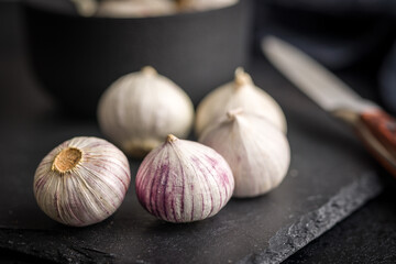 Solo glove garlic bulbs on black table.