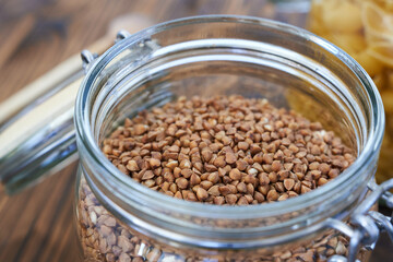 Buckwheat in a glass jar on a wooden background.