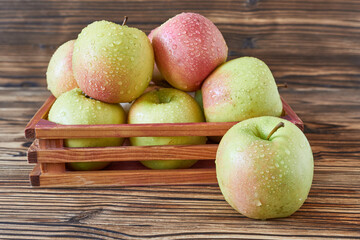 Ripe apples in a wooden box on a wooden background. Close-up.