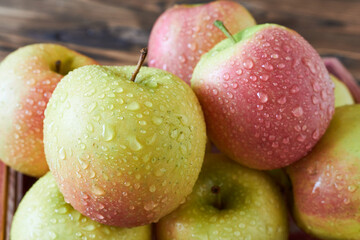 Ripe apples with drops of dew on a wooden background.