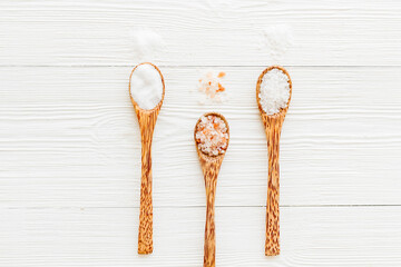 Different kind of sea salt in wooden spoon, top view. Salt for spa, salt baths or cooking