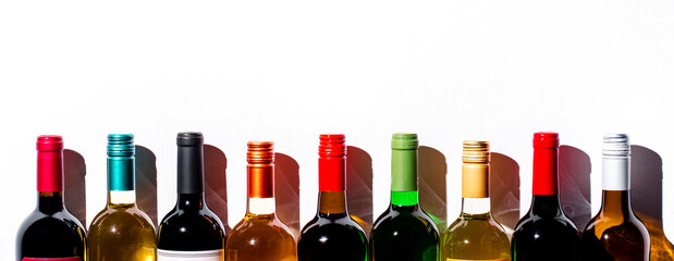 Wine bottles collection row in wine shop, restaurant or bar on white background. Multi-colored wine...