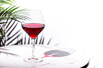Non-alcoholic, alcohol fries, red wine in glass. White background, palm leaves shadows, hard light