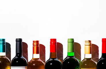 Wine bottles collection row in wine shop, restaurant or bar on white background. Multi-colored wine...