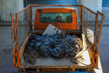 Orange Utility Truck Loaded with Black Garbage Bags at Construction Site During Cleanup
