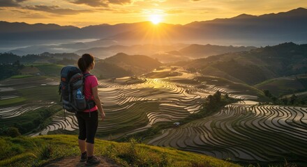 Fototapeta premium Hiker watching golden sunrise over terraced rice fields