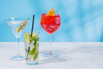 A variety of cocktails arranged on a table against a light blue background