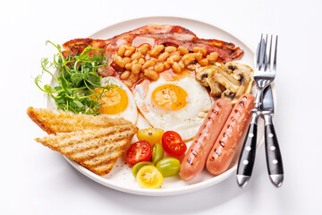 A classic breakfast plate featuring sunny-side-up eggs, crispy bacon, sausages, and fresh tomatoes