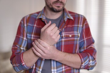 Man suffering from wrist pain at home, closeup