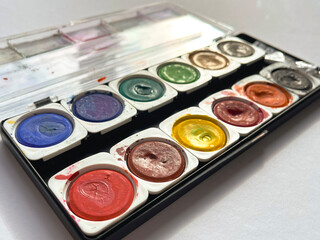 Dirty watercolor paints set with brushes after using