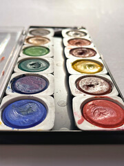 Different set of watercolors in the box on a white background