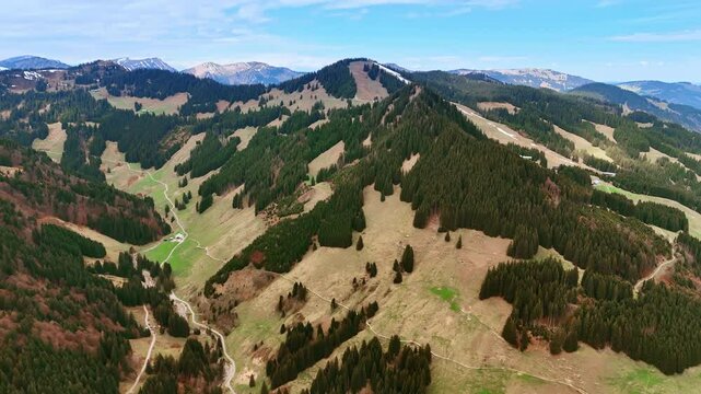 Pine tree forests grow on the slopes of the mighty mountains. Rocky landscape of Bavaria, Germany from aerial view.