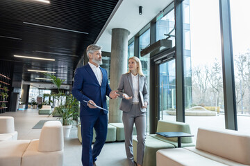 Businesspeople wearing suits walking together smiling while talking about company projects