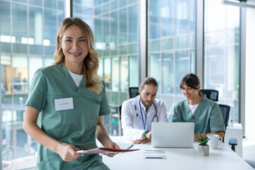 Portrait of blonde woman doctor with man colleague and nurse talking on background