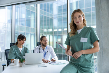 Beautiful female medical doctor smiling while her colleagues sitting in background