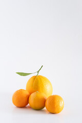 A fresh, rich and healthy orange and several tangerines with leaf resting on white background