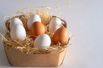 Brown and white chicken eggs are nestled in a bed of raffia, ready for cooking or easter decoration