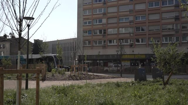 A modern trolleybus glides through Rue Saint-Georges in Nancy, France, blending seamlessly into the historic urban landscape. The sleek electric vehicle moves past classic French architecture