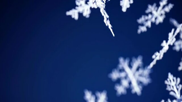 Close-up video of delicate snowflakes against a deep blue background, captured from a low angle, highlighting intricate patterns and details. Live desktop wallpaper.