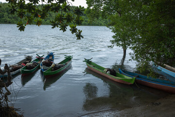 Fototapeta premium East Sumba – 04. 20. 2025 – Colorfully painted boats equipped with fishing gear are parked at the mouth of the river near the Kawangu fishing village