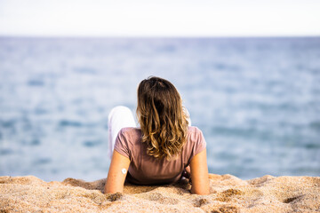 Woman with continuous glucose monitor relaxing on beach enjoying ocean view