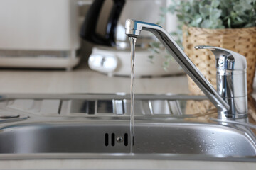Water flowing from a modern kitchen faucet in a bright setting