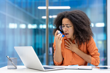 An office worker is experiencing an asthma attack. She struggles to breathe while reaching for her...