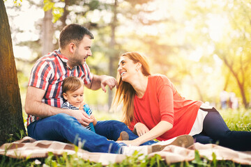 Fototapeta premium Portraits of happy family outdoors with their baby boy. Shallow DOF. Developed from RAW; retouched with special care and attention; Small amount of grain added for best final impression.