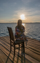 Fototapeta premium Woman and child relaxing on the pier by the sea during sunset