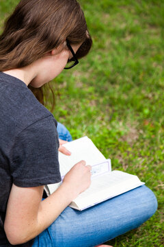 Teen girl reading a book outside