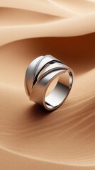 Fototapeta premium Geometric silver ring with intersecting lines on warm sand background