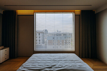Cozy bedroom with a bed and a window featuring decorative blinds