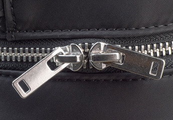 Close-up view of a zipper on a black fabric material