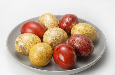 Red and yellow chicken eggs with glitter on a gray plate. Easter painted eggs. Chicken egg with glitter. Traditional Christian food for Easter