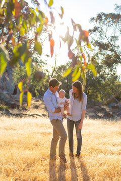 Young parents standing outdoors with their baby