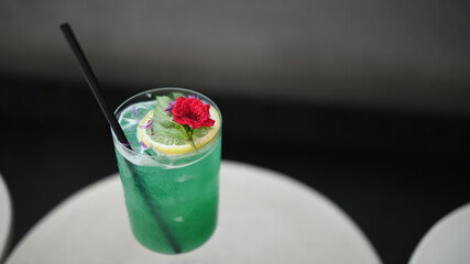 Close-Up of Green Cocktail with Floral and Citrus Garnish